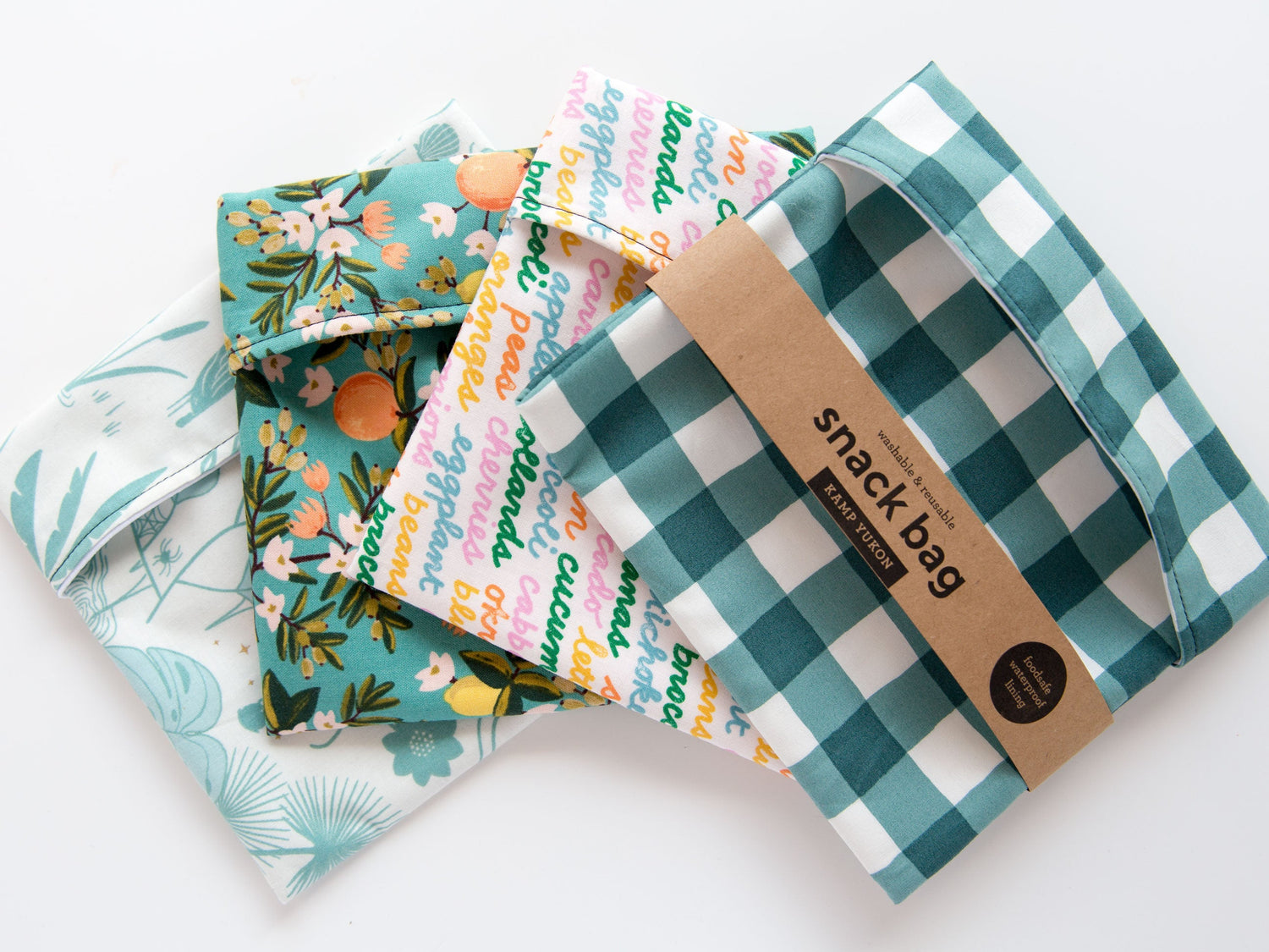 4 green and blue snack bags laid out with kraft paper packaging