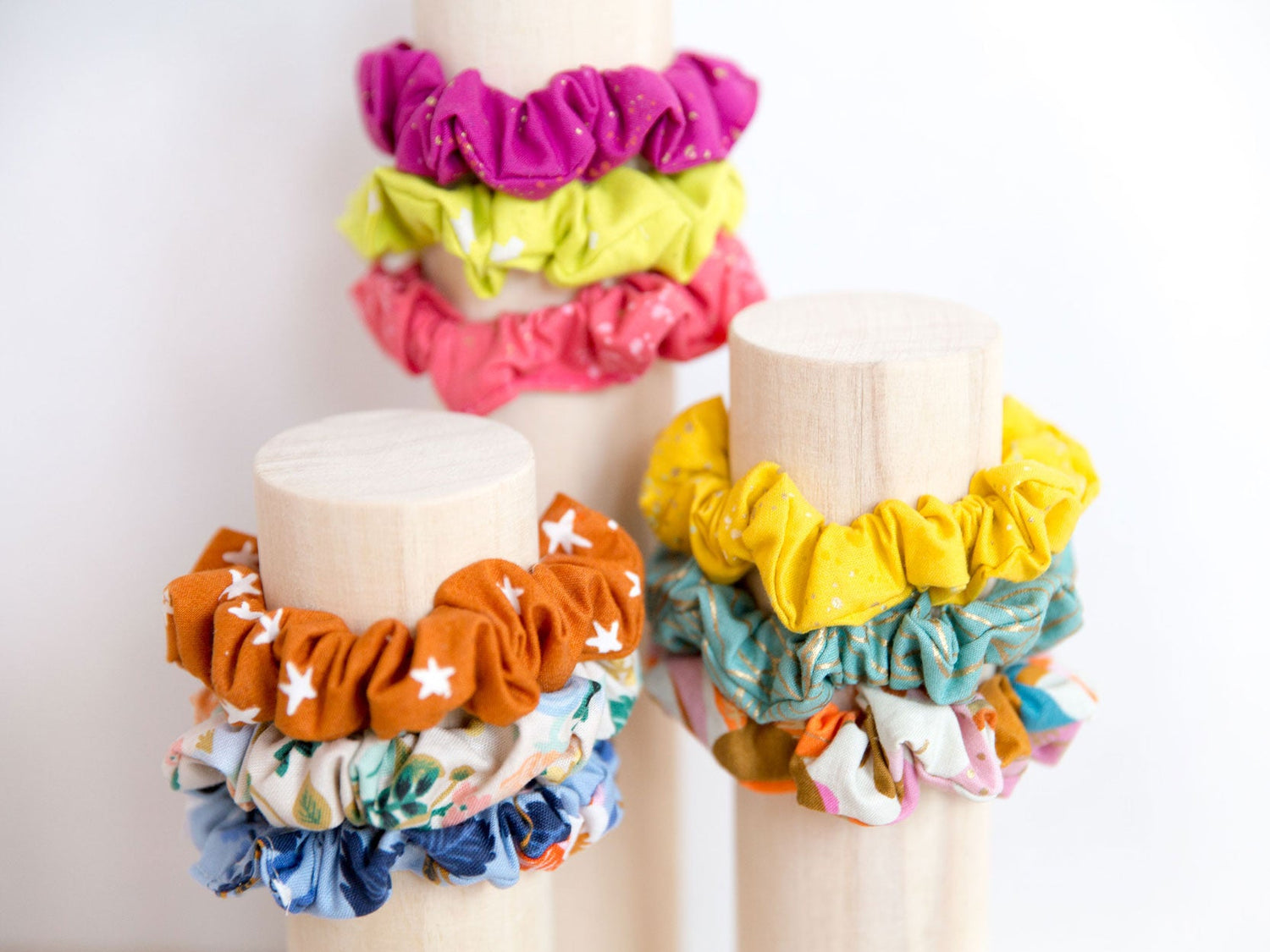 Three large wooden dowels with colourful scrunchies wrapped around them