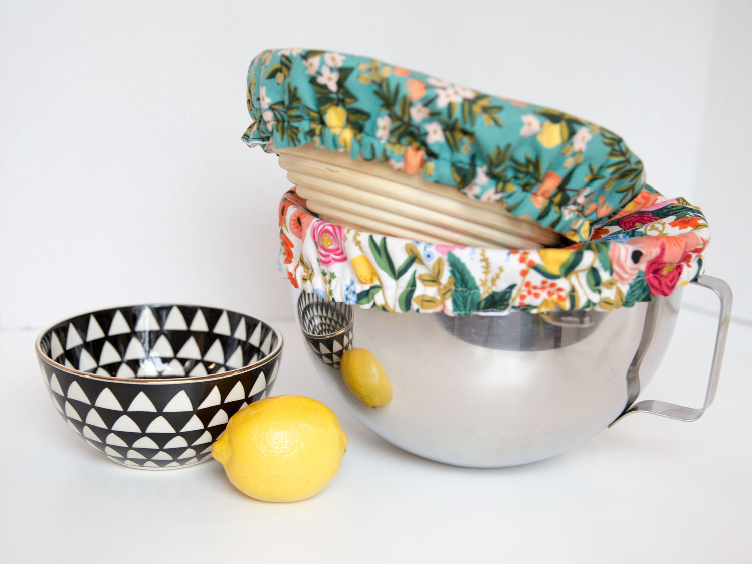 benneton proofing basket with a teal bowl cover stacked on top of a stand mixer bowl with a floral bowl cover