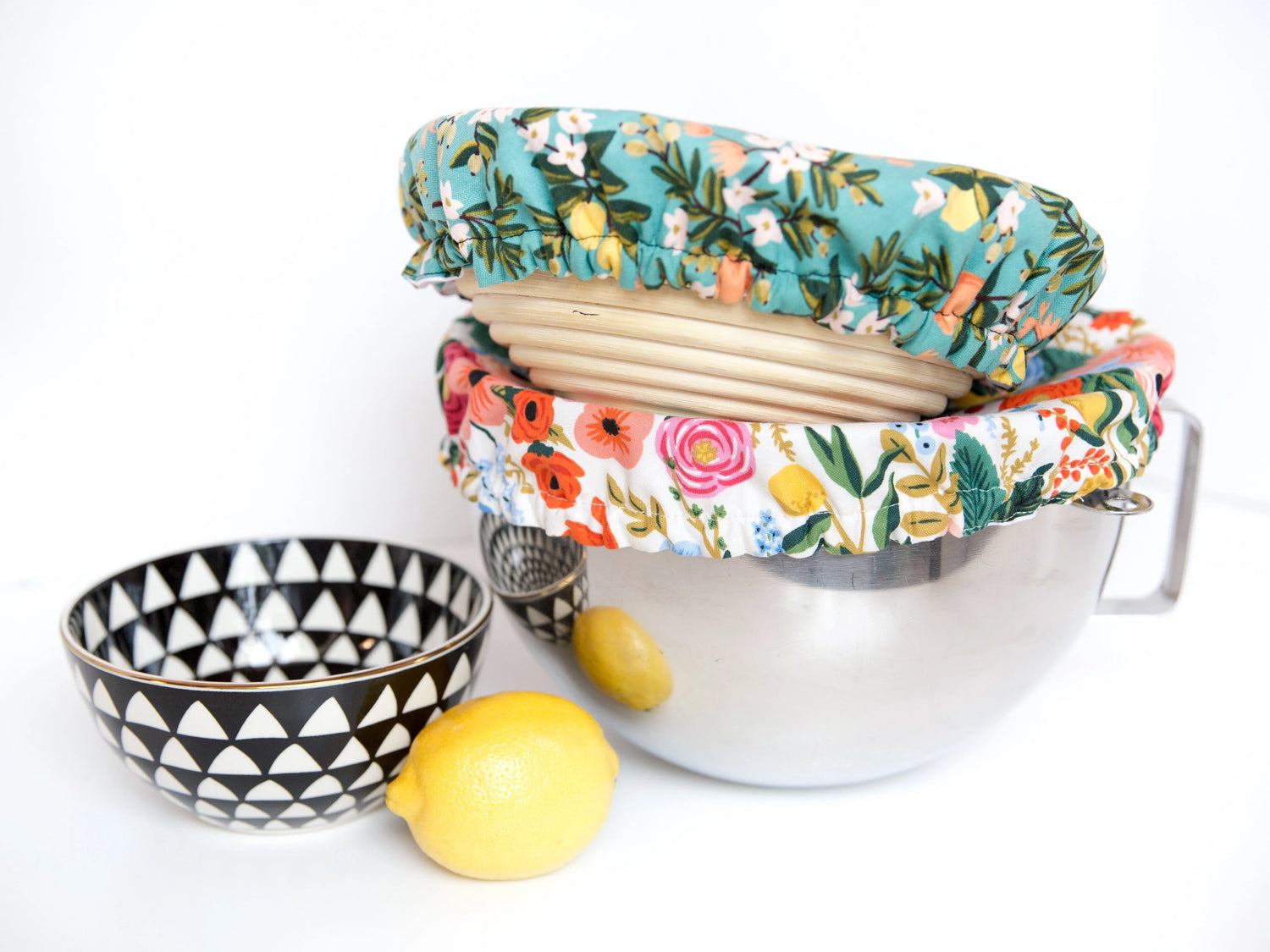 KitchenAid stand mixer bowl with a floral bowl cover. A banneton proofing basket with a teal bowl cover sitting on top. a decorative bowl and lemon beside those A decorative bowl and lemon sitting beside those.