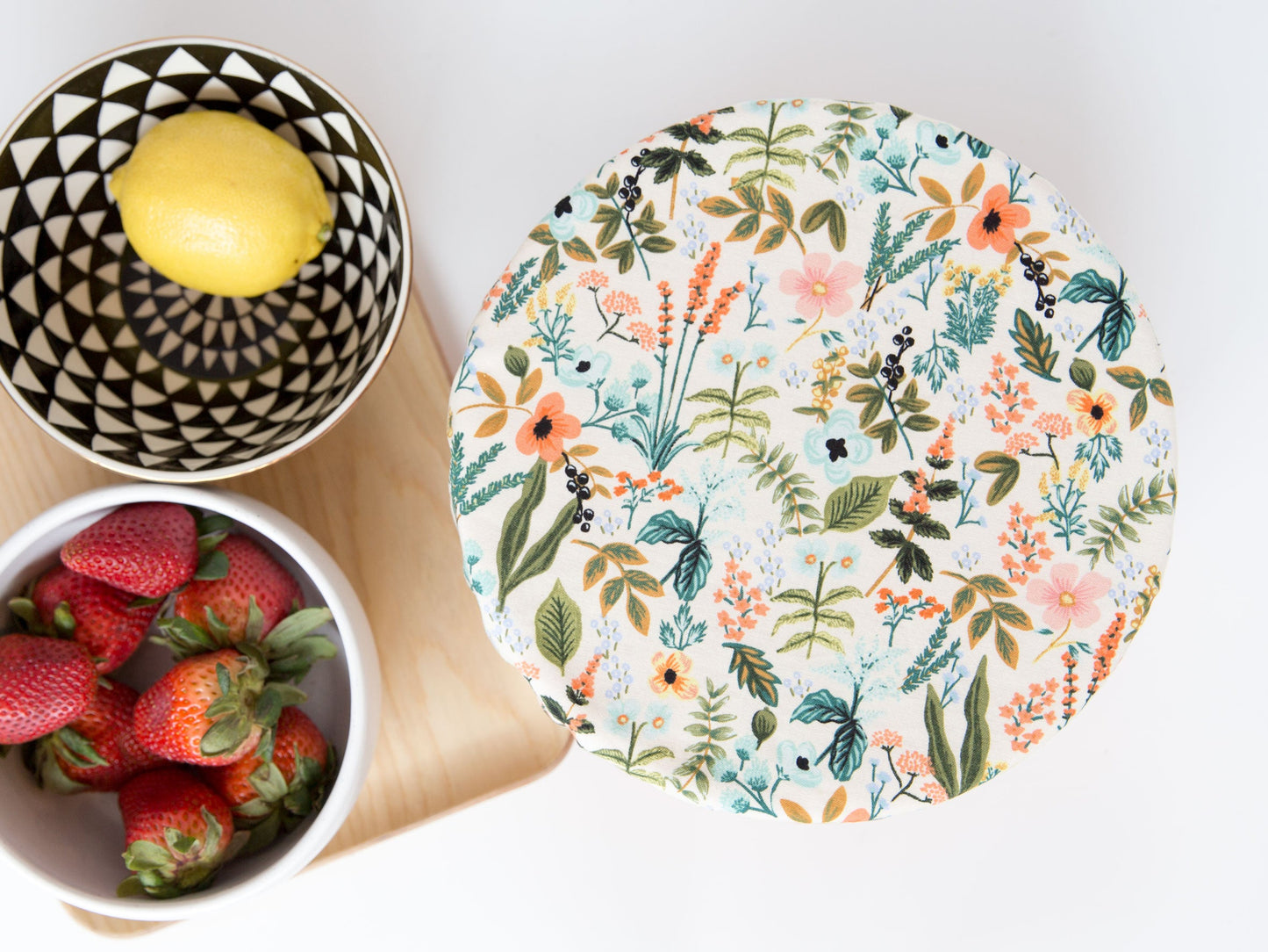 floral bowl cover beside bowls of lemon and strawberries
